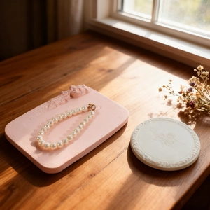 Floral embossed resin tray with round pearl necklace on wooden surface with natural light