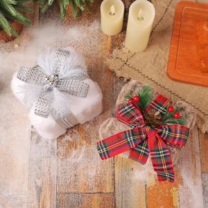 Plush Christmas gift box ornaments with silver and plaid bows on snowy wood background