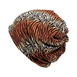 Detail showing the soft tiger print fabric texture and layered folds of the orange beanie