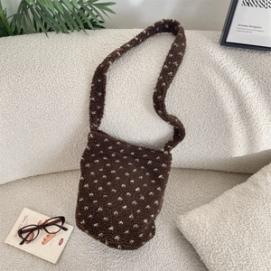 Detail of plush fleece brown bucket bag with white polka dots on soft fabric