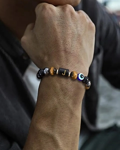 Close-up of beaded tiger eye bracelet with evil eye charm and letter J on a male wrist