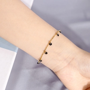 Macro view of minimalist golden chain bracelet with elegant black round gemstone charms