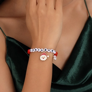 Detail of Santa Baby beaded bracelet with red charms on a model in green velvet