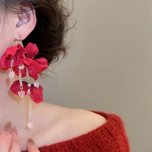 Detailed view of red fabric flower earrings with pearl and heart tassel charms