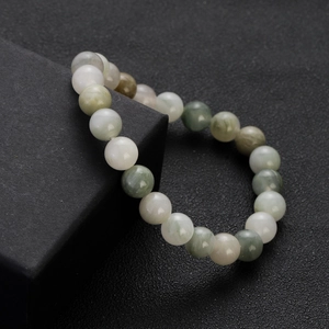 Close-up of polished natural stone beads in green and white on a black jewelry box