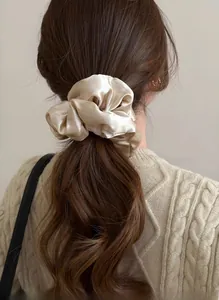 Close-up of champagne satin oversized scrunchie on hair with elegant silk shine finish