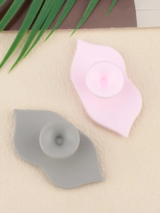 Detailed view of pink and grey silicone lip brushes with suction cup on beige background
