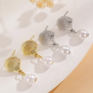 Detail of scallop shell earrings with pearls in gold and silver finish on soft background