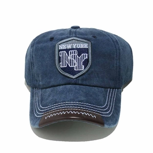 Detailed embroidery on a vintage navy denim baseball cap with leather trim on the brim