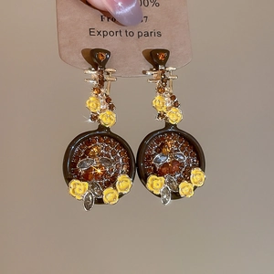 Macro di orecchini a fiore con pavé di cristalli ambrati e dettagli in oro vintage