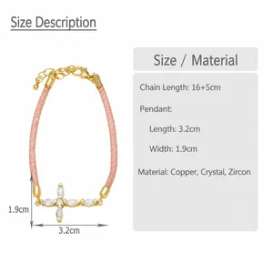 Detalle macro de la pulsera de cruz bañada en oro con circonitas y cordón rosa