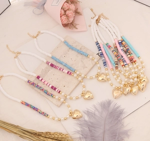 Detail showing various handmade polymer clay bead necklaces with gold heart pendants