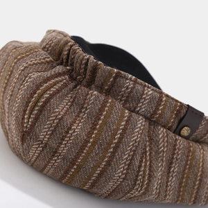 Detail of tweed newsboy cap showing elastic back and leather strap with metal button