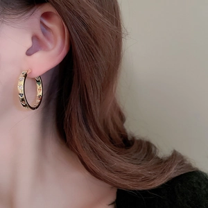 Golden hoop earrings with colorful heart zircons worn by a model in a close-up shot