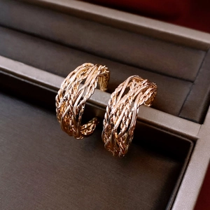 Détail macro de boucles d'oreilles en C plaquées or 18 carats avec texture tissée élégante