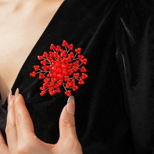 Close-up of red beaded flower brooch with gold wire on black velvet clothing