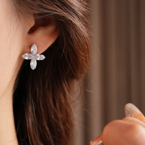 Gros plan d'élégantes boucles d'oreilles trèfle en argent et zircon sur un mannequin