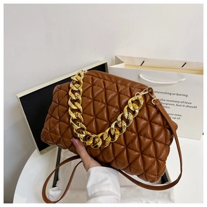 Detailed view of brown quilted crossbody bag with chunky gold chain handle and luxury packaging