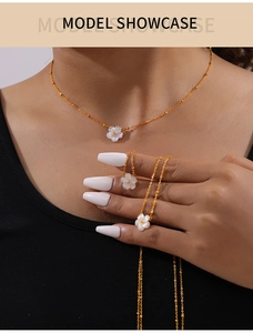 Detail of 18K gold-plated necklace with white shell flower pendant on model neckline