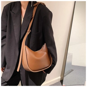 Sacoche demi-lune en cuir marron portée avec un blazer noir surdimensionné sur un mannequin