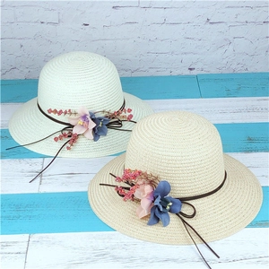Dettaglio di cappelli da sole in paglia con fiori su sfondo di legno e mattoni