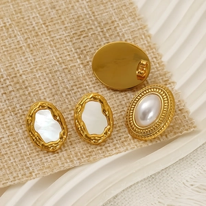 Vintage oval pearl earrings with irregular gold plating on rustic linen and ceramic base