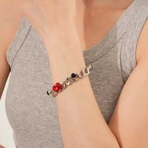 Detail of silver chunky chain bracelet with red and black stones on model wrist