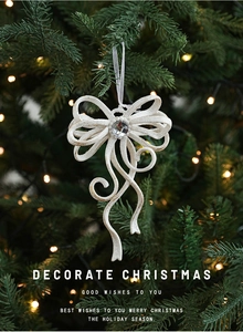 Close-up of a white glittery bow ornament with a faux gemstone on a Christmas tree