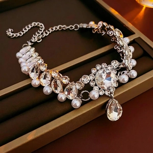 Luxury silver flower necklace with teardrop crystal and pearl accents on brown tray