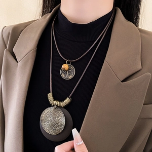 Détail d'un collier en cuir multicouche avec pendentifs en bronze vintage sur mannequin