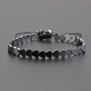 Adjustable black hematite heart bead bracelet with high-gloss braided cord on grey background