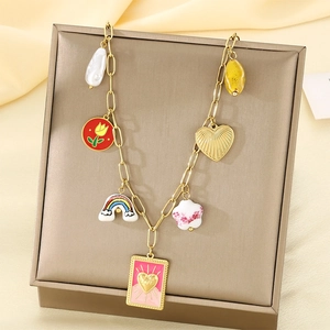 Gros plan de breloques dorées avec perle, arc-en-ciel et cœur rose sur un présentoir à bijoux