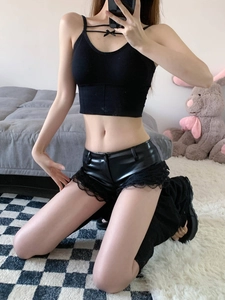 Dettaglio di pantaloncini in pelle PU con finiture in pizzo nero e top aderente con fiocco