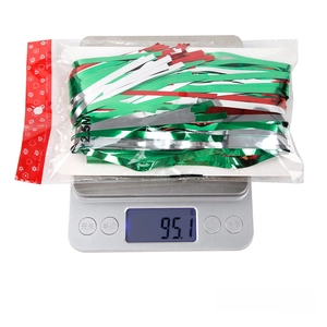 Weighing of red, green, and silver metallic fringe curtain showing 95.1g on scale