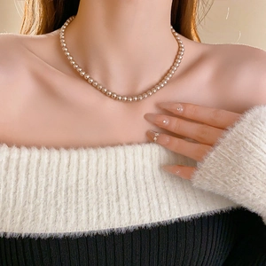 Elegant French vintage pearl necklace worn by a model on a bicolor off-shoulder sweater