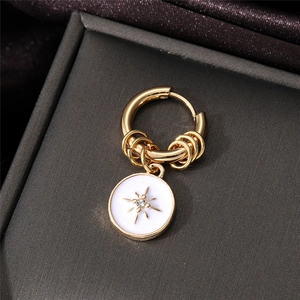 Macro shot of gold hoop earring with starburst charm and crystal in jewelry box