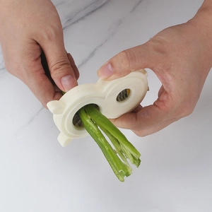 Manual stainless steel vegetable shredder for green beans on white marble background