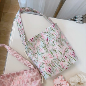 Detailed embroidery on fabric tote bags featuring pink heart and blue floral patterns