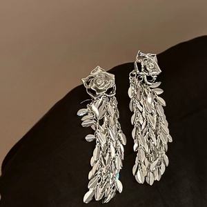 Détail de boucles d'oreilles rose argentée avec glands en feuilles de saule métal