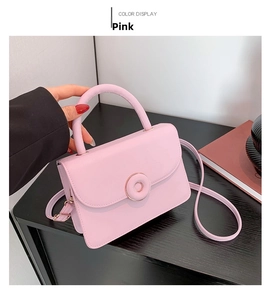 Close-up of pink PU leather handbag showing round metal buckle and smooth stitched texture