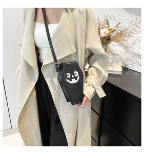 Ghost coffin shaped crossbody bag with pumpkin print on a model wearing a stylish trench coat