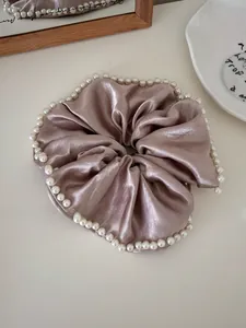 Close-up of champagne pink satin scrunchie with elegant faux pearl trim edge detail