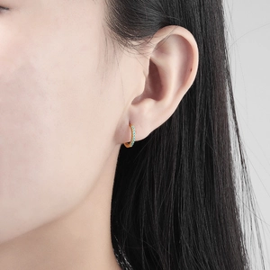 Fashionable gold hoop earrings with inlaid turquoise stones worn by a female model