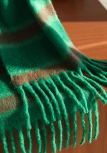 Macro detail of soft striped scarf with green and brown plaid weave and fringe