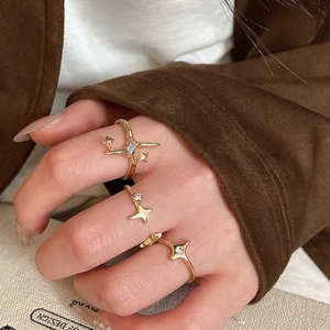 Detailed view of three-piece gold starburst ring set with zircon on model's hand
