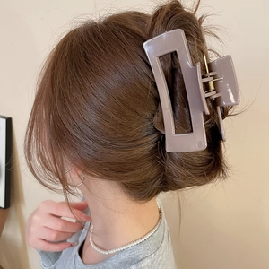 Detail view of large taupe square claw clip securing hair in a back bun hairstyle