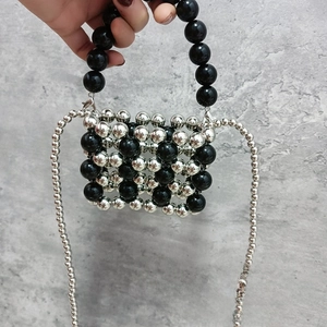 Detailed close-up of a mini silver and black beaded handbag with a metallic chain strap