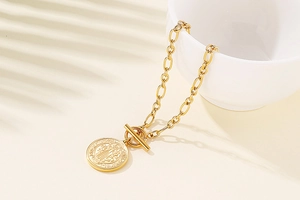 Detailed shot of golden Saint Benedict coin pendant bracelet with a T-bar toggle clasp