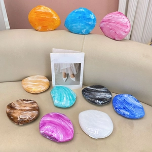 Macro shot of colorful pebble-shaped acrylic clutch bags with artistic marble texture