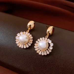 Macro detail of gold plated pearl earrings with radiant cubic zirconia accents